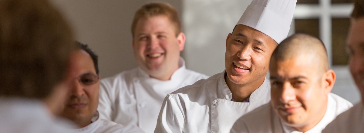 Group of Compass chefs smiling and listening at a team meeting